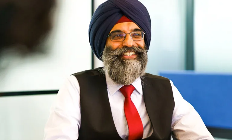 A man smiles in an brightly lit meeting room setting