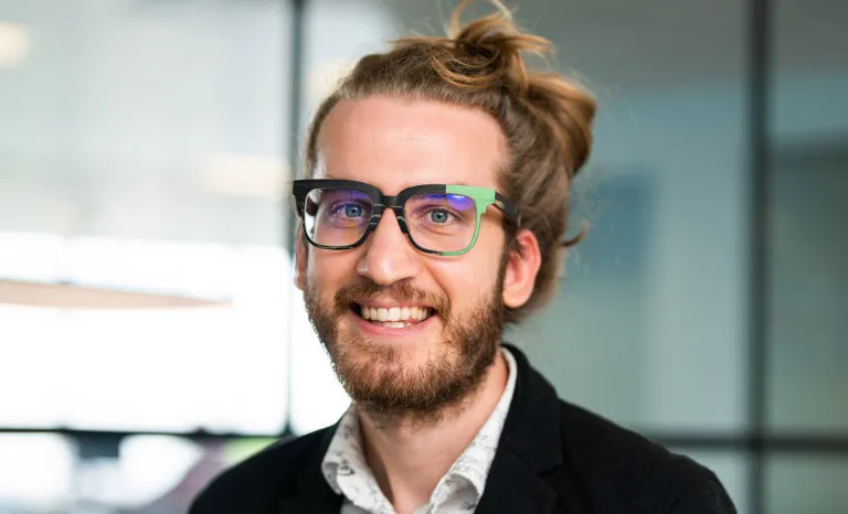 Portrait shot of a man in an office setting smiling to camera