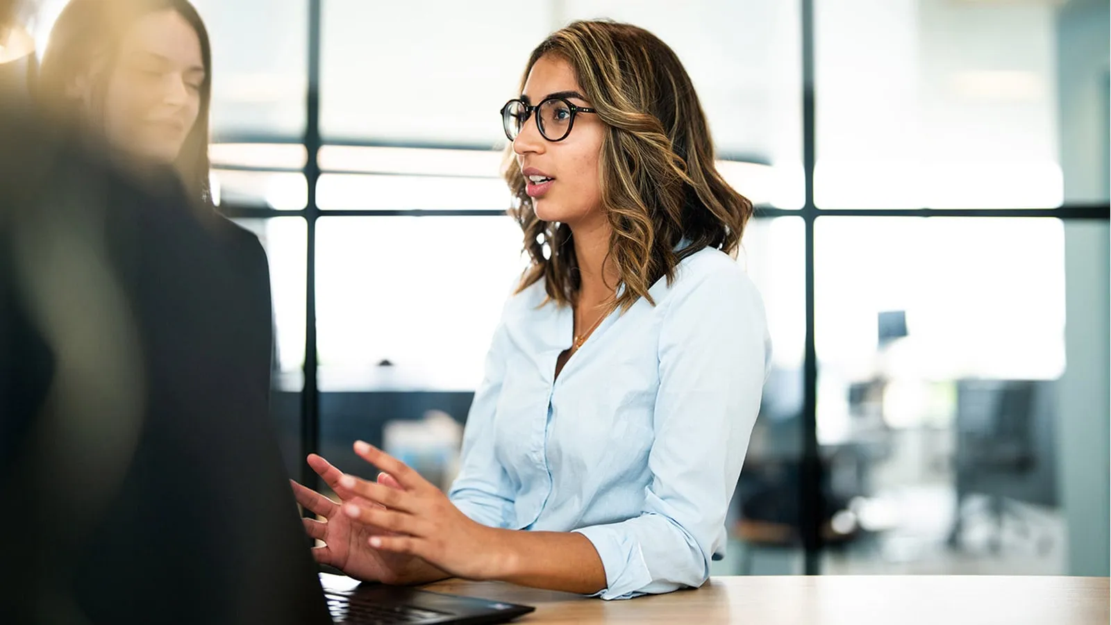 Young Woman in Bright Office Talking to Colleagues