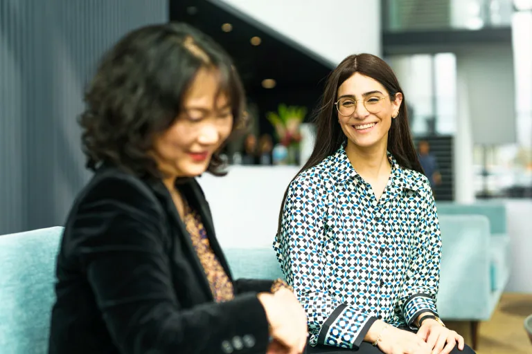 Two colleagues take a break in an office kitchen setting