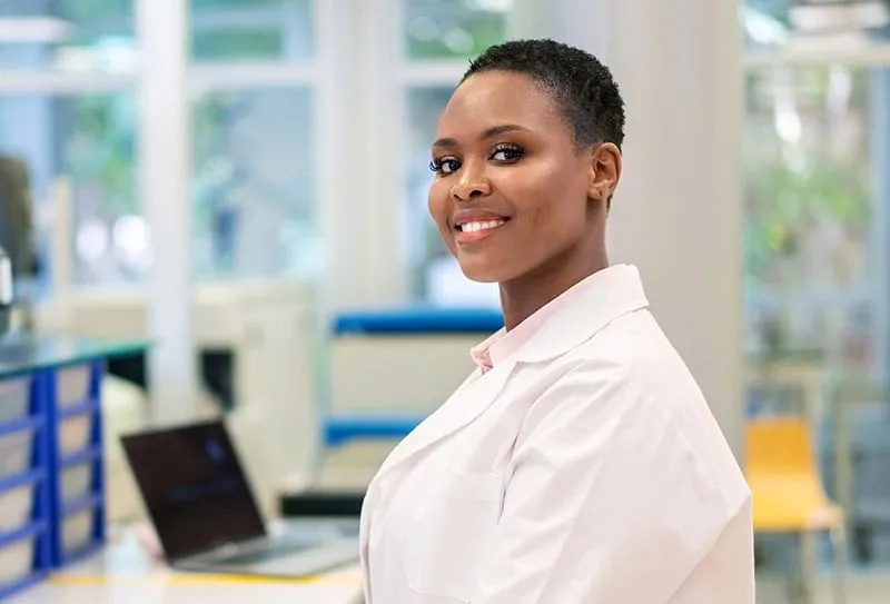 A Cheerful Woman in a Lab Coat Smiles in a Laboratory Context