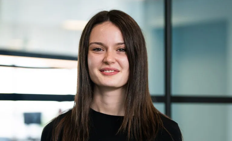 Portrait shot of a woman in an office setting smiling to camera