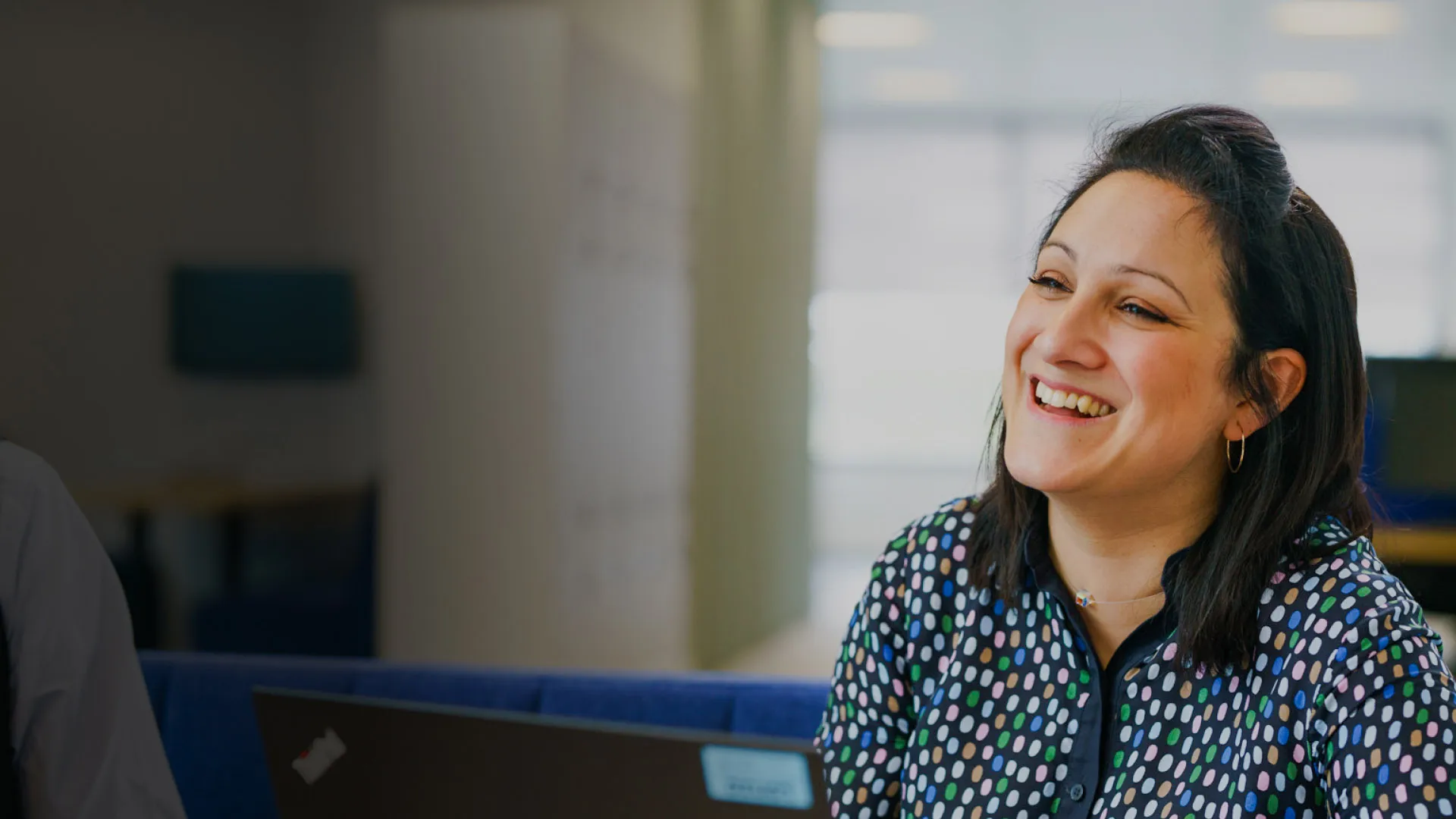 A zoomed in shot of a woman smiling at her desk