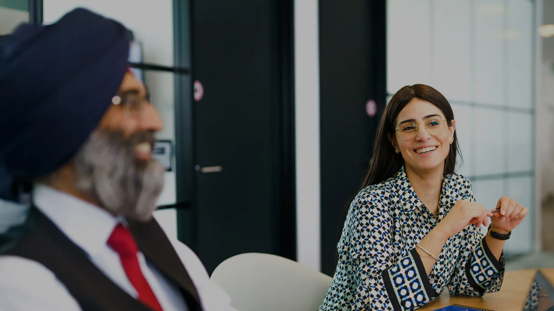 Two colleagues laugh in a meeting in an office room