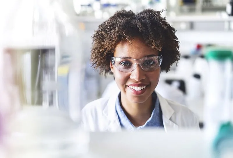 A Smiling Woman in a Lab Coat in a Laboratory Setting.