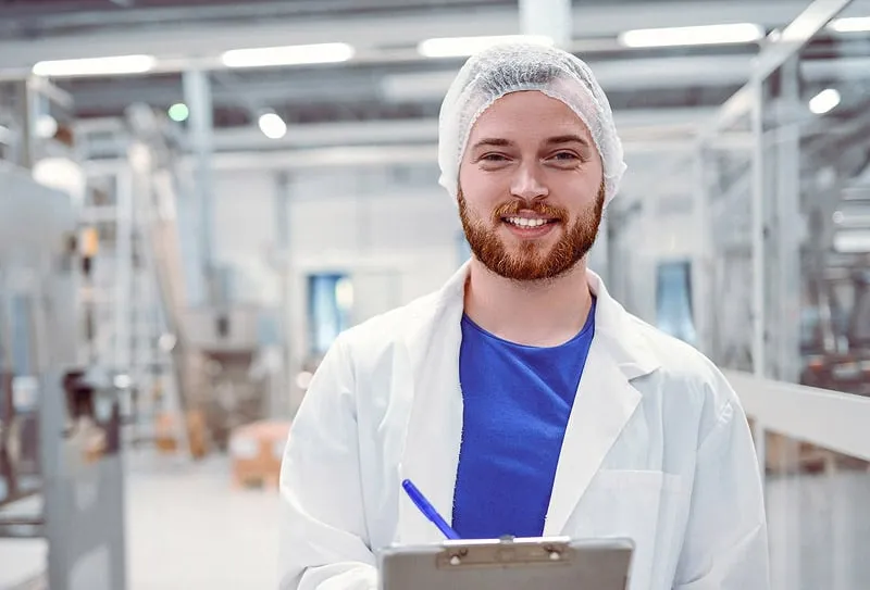 A Smiling Man in a Lab Coat Poses for the Camera, Conveying a Friendly and Professional Demeanor.