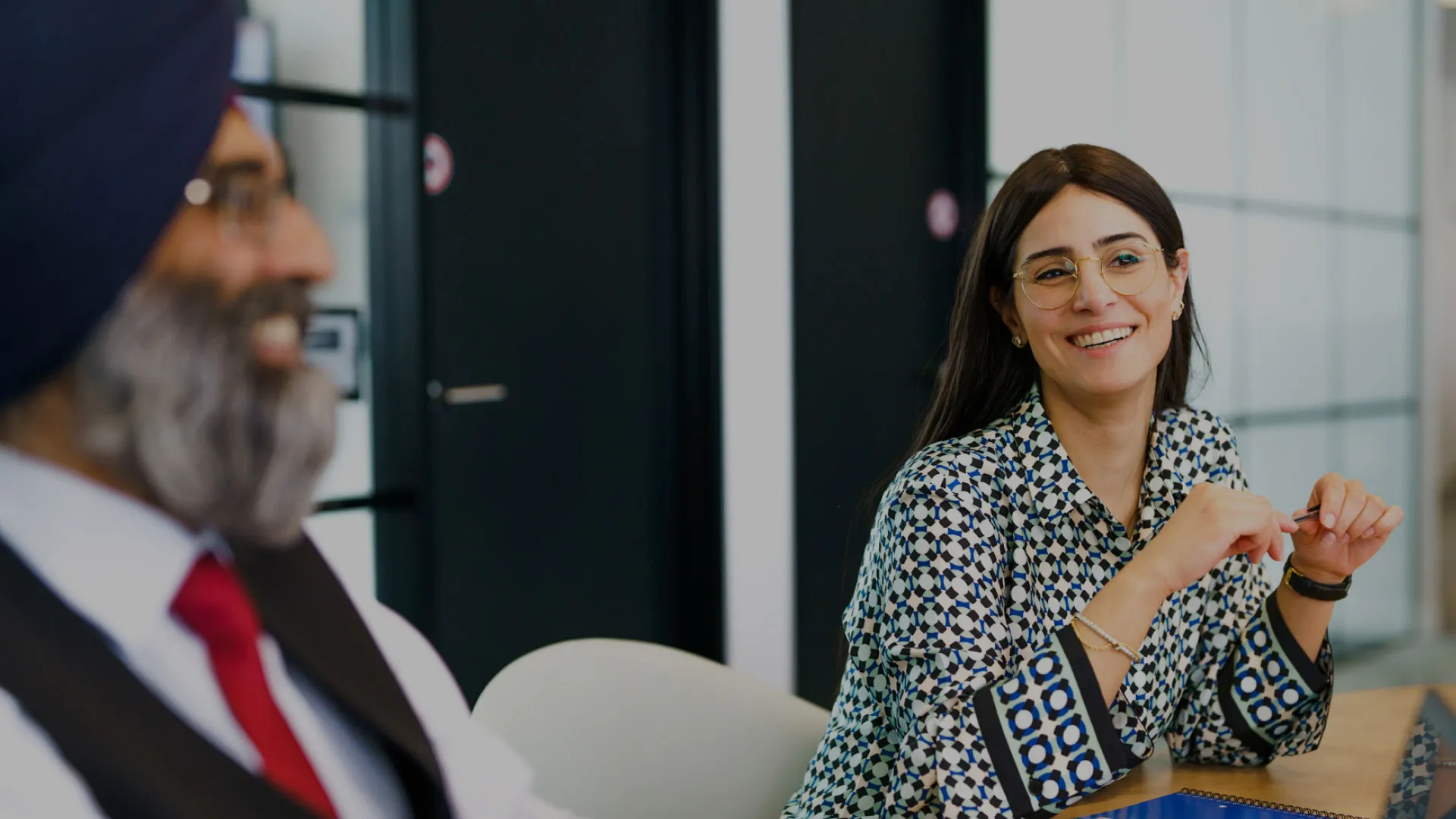 Two colleagues laugh in a meeting in an office room