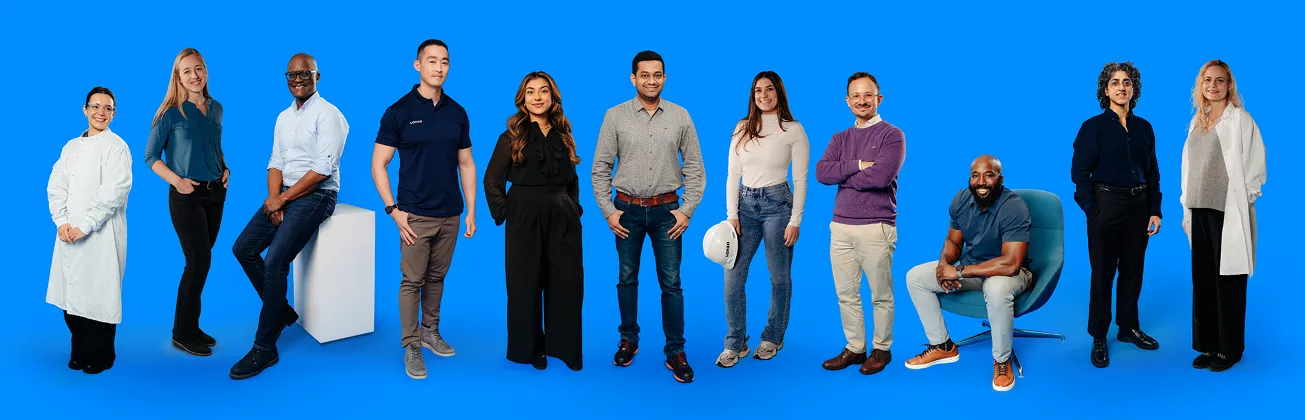 A Diverse Group of Ten Professionals Standing and Sitting in a Row Against a Solid Blue Background.